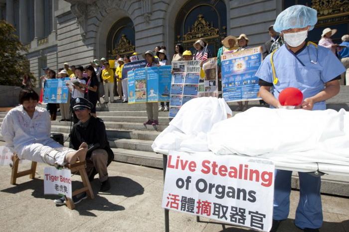 Актёры имитируют методы пыток, применяемых к последователям Фалуньгун в Китае, в то время как демонстранты держат плакаты. Сан-Франциско, 5 сентября. Фото: Epoch Times