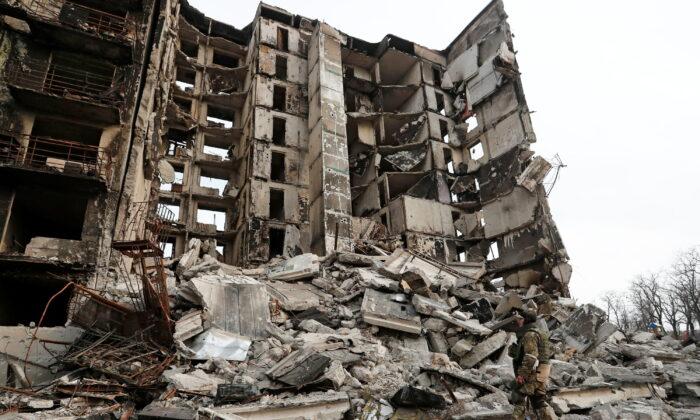 Военнослужащий пророссийских войск стоит на руинах разрушенного жилого дома в Мариуполе, Украина, 30 марта 2022 года. Фото: Александр Ермоченко/Reuters
 | Epoch Times Media