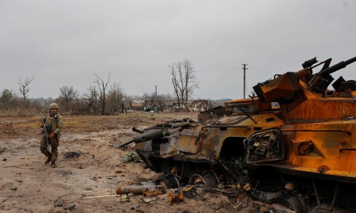 Украинский военнослужащий осматривает уничтоженный российский бронетранспортёр БТР-82 в селе недалеко от линии фронта, Киевская область, Украина, 31 марта 2022 г., Украина, 31 марта 2022 г. (Serhii Nuzhnenko/Reuters)
 | Epoch Times Media