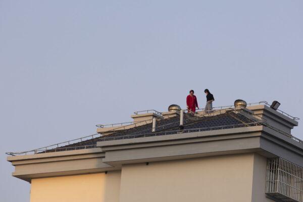 Люди стоят на крыше жилого дома в Шанхае 11 апреля 2022 года. (AP Photo)