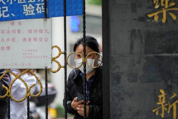 Житель выглядывает из-за ворот, перекрывающих вход в жилой район, находящийся под блокировкой, в Шанхае 13 апреля 2022 года. (Aly Song/Reuters)