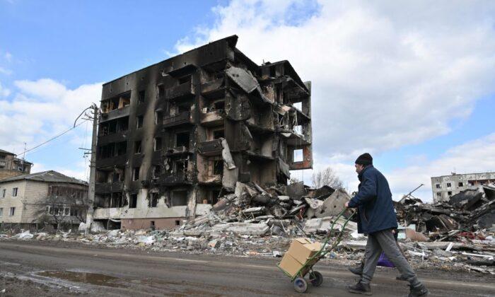 Человек проходит мимо разрушенных зданий в городе Бородянка к северо-западу от Киева, 4 апреля 2022 года. (Фото: Sergein Supinsky/AFP via Getty Images)
 | Epoch Times Media