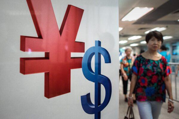 Плакат со знаками юаня (слева) и доллара США (справа) в Гонконге 13 августа 2015 года. (Philippe Lopez/AFP via Getty Images)