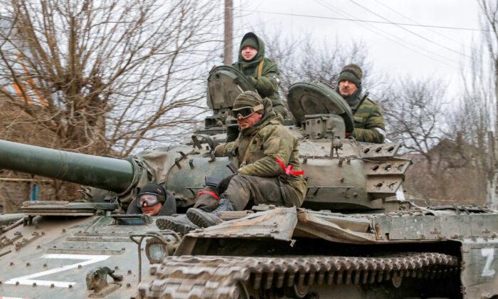 Российские военные в форме стоят на вершине танка с нарисованной на боку буквой 