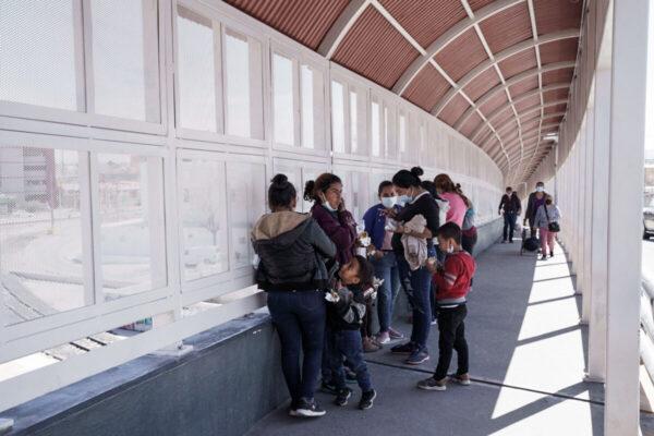 Группа нелегальных иммигрантов, которых быстро депортируют из США в соответствии с разделом 42, ждёт на мексиканской стороне международного моста Пасо-дель-Норте между Эль-Пасо, штат Техас, и Сьюдад-Хуаресом, Мексика, 10 марта 2021 года. (Paul Ratje/AFP via Getty Images)