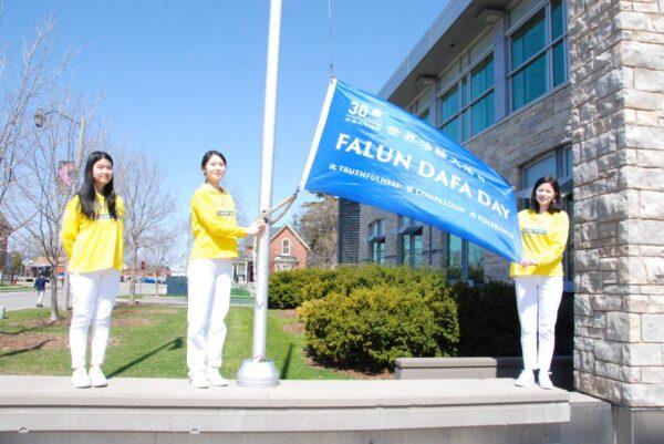 Последователи Фалунь Дафа поднимают флаг в честь 30-й годовщины распространения духовной практики в городе Милтон, Онтарио, 2022 мая. Фото: Arek Rusek/The Epoch Times