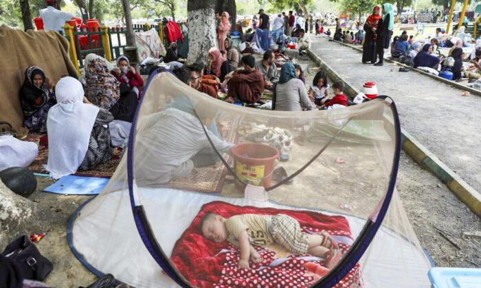 Афганский мальчик спит под москитной сеткой, когда перемещённые лица установили на земле самодельные палатки у здания пресс-клуба в Исламабаде, 9 мая 2022 года. (Rahmat Gul/AP Photo)
 | Epoch Times Media