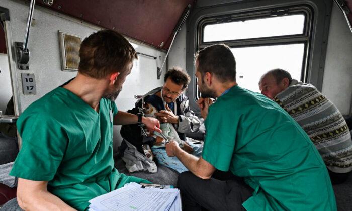 Врачи MSF оказывают помощь пациенту в поезде медицинской эвакуации, направляющемся во Львов на западе Украины, 10 апреля 2022 года. (Genya Savilov/AFP via Getty Images)
 | Epoch Times Media