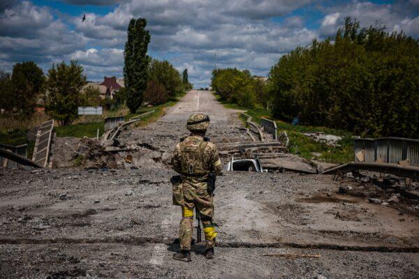 Боец украинского спецназа «Кракен» наблюдает за местностью у разрушенного моста на дороге возле села Русская Лозовая, к северу от Харькова, 16 мая 2022 года. (Dimitar Dilkoff/AFP via Getty Images)