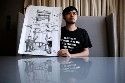 Политический иллюстратор А То со своей работой «Гильотина» после закрытия его колонки карикатур в одном из популярных городских новостных журналов, Китай, 28 июля 2020 года. (Tyrone Siu/Reuters)