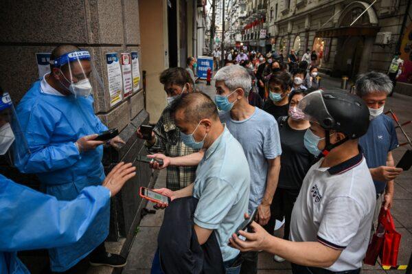 Рабочие сканируют QR-коды здоровья людей, входящих в торговый центр в районе Хуанпу в Шанхае 1 июня 2022 года. (Hector Retamal/AFP via Getty Images)