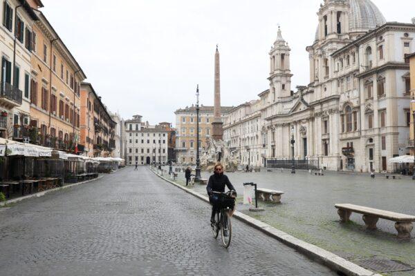 13 марта 2020 года на совершенно пустой площади Навона в Риме была замечена женщина, катающаяся на велосипеде. Улицы города были устрашающе тихими на второй день общенационального закрытия школ, магазинов и других общественных мест. (Marco Di Lauro/Getty Images)