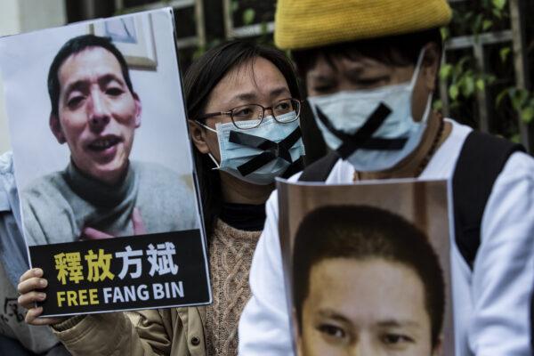 Активист-демократ (справа) из HK Alliance держит плакат с изображением пропавшего гражданского журналиста Фан Биня во время протеста у офиса связи Китая в Гонконге 19 февраля 2020 года. (Isaac Lawrence/AFP via Getty Images)