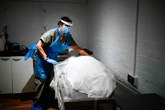 Бальзамировщик использует средства индивидуальной защиты при подготовке умершего человека в Шипли, Англия, 21 мая 2020 г. (Christopher Furlong/Getty Images)