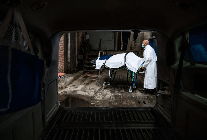 Сотрудник Maryland Cremation Services переносит тело жертвы COVID-19 в фургон из морга больницы в Балтиморе, штат Мэриленд, 24 декабря 2020 г. (Andrew Caballero-reynolds/AFP via Getty Images)